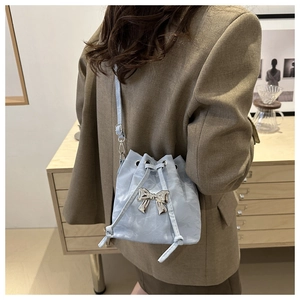 Close-up of light blue drawstring bucket bag with silver butterfly and marble texture