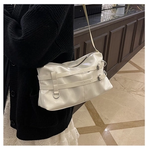 Detail of white glossy shoulder bag featuring silver metal rings and buckle straps