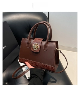 Detail of brown crocodile pattern handbag with elegant golden floral metal clasp