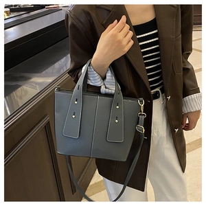 Detail of grey textured leather bucket bag with gold hardware and white contrast stitching