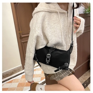 Detail of minimalist black crossbody bag with leather strap and silver metal buckle