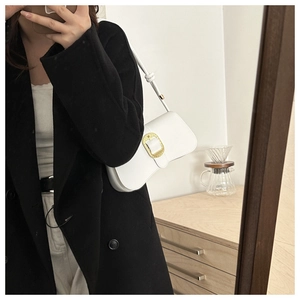 Detailed view of a white leather underarm bag featuring a textured gold metal buckle