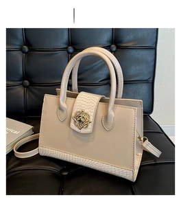 Detail of khaki crossbody bag with crocodile texture and gold floral metal buckle