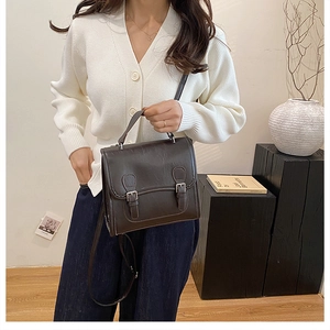 Close-up of retro dark brown leather bag with dual buckles and adjustable shoulder strap