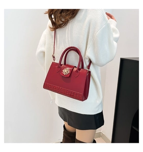 Detail of red leather handbag with gold flower clasp and textured crocodile embossing