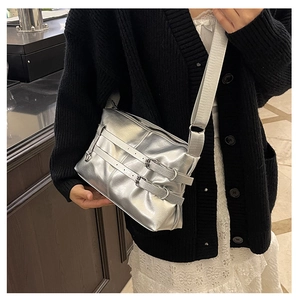Detail of silver metallic crossbody bag featuring adjustable double buckle straps