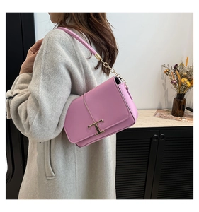 Vue latérale d'une femme portant un sac en cuir mauve avec boucle en T dorée iconique