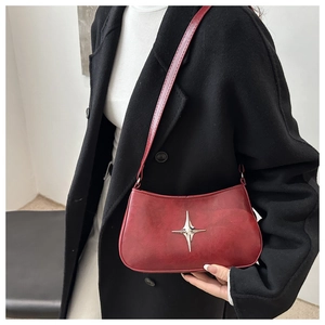 Détail du sac porté épaule rouge en cuir ciré vintage avec boucle étoile et bandoulière