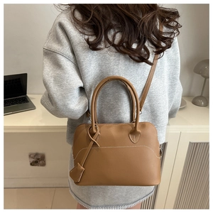 Dettaglio di una borsa a mano in pelle marrone con cuciture a contrasto e tracolla