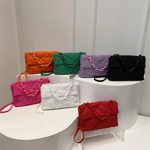Quilted crossbody bag with chain handle in multiple colors displayed on white stairs