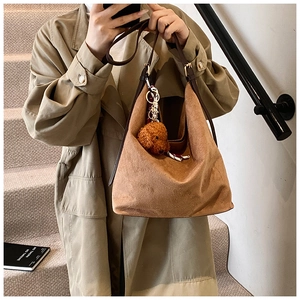 Detail of vintage brown suede tote bag with plush bear charm and decorative silk scarf