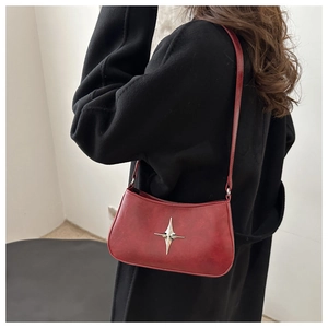 Détail du sac croissant rouge foncé avec breloque étoile argentée et texture cuir mat