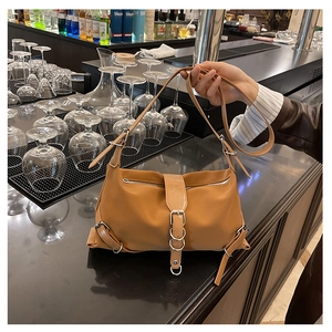 Detail of caramel shoulder bag with silver metal ring and decorative leather belt