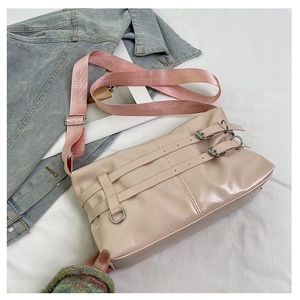 Detail of pink PU leather shoulder bag with decorative double buckle straps and nylon strap