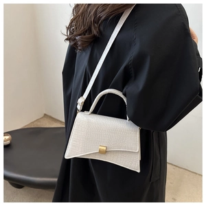 Model wearing a white crocodile embossed small square bag with golden buckle on black coat