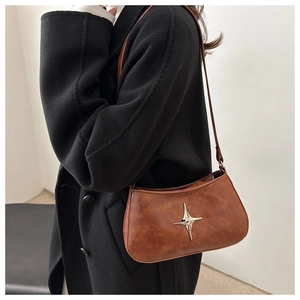 Gros plan d'un sac porté épaule marron vintage avec détail étoile sur manteau noir
