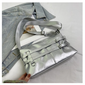 Detail view of silver metallic shoulder bag with double belt buckles and textile strap