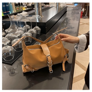 Detail of camel leather handbag with functional buckle strap and silver metal ring hardware