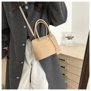 Dettaglio della borsa tote beige minimalista con cuciture e doppi manici in un interno casa