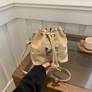 Chic beige drawstring bucket bag with marble texture leather and silver bow accessory