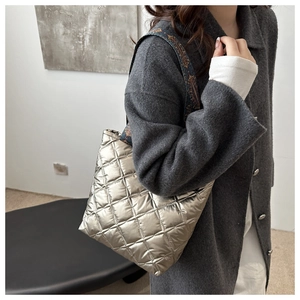 Detailed close-up of champagne gold quilted tote with ethnic pattern wide strap