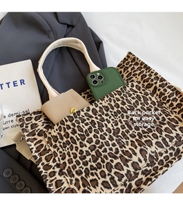 Detailed view of leopard print tote bag back pocket holding a smartphone and wallet