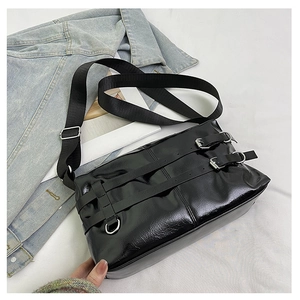 Detail of glossy black patent leather tote with silver metal buckles and nylon strap