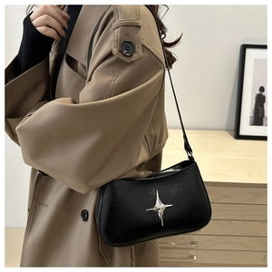 Gros plan du sac hobo noir brillant avec détail décoratif en métal en forme d'étoile