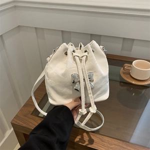 Chic white drawstring bucket bag with metallic bow and textured ripple finish