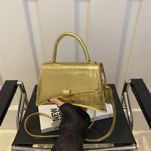 Chic gold crocodile embossed trapezoid shoulder bag with unique curved base design