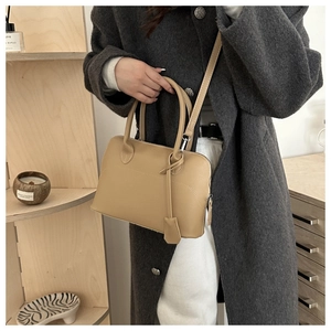 Dettaglio della borsa tote in pelle marrone chiaro con struttura ad arco e manici