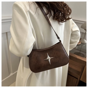 Détail du sac porté épaule vintage marron avec étoile argentée et cuir à texture cirée