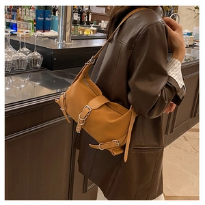 Detail of ginger leather shoulder bag with silver buckles styled with a brown jacket