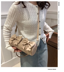 Beige cylindrical pillow bag with oversized twin bows shown in a crossbody style
