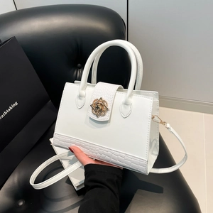 White crocodile embossed handbag with a golden floral lock and adjustable shoulder strap