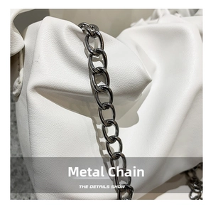 Close-up of vintage white pleated leather handbag with thick dark grey metal chain strap