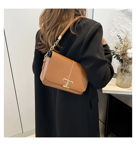 Détail du sac bandoulière en cuir caramel avec fermoir doré en T et bandoulière chaîne