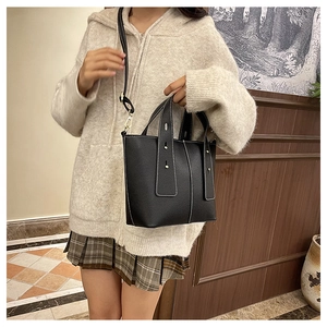 Chic black lychee grain bucket bag with white contrast stitching on a female model