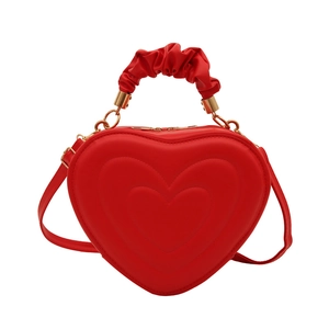 Sac à main rouge en forme de cœur avec poignée plissée et détails dorés sur fond blanc
