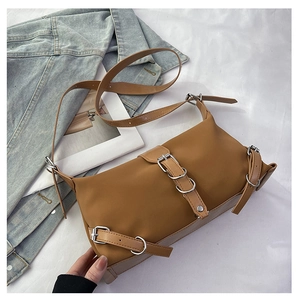 Detail of brown rectangular shoulder bag with silver buckles on white fabric background