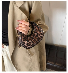 Detailed view of leopard print crescent bag on model with gold hardware and zippers