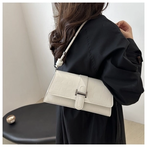 Close-up of a white crocodile texture underarm bag with a silver buckle and knotted strap