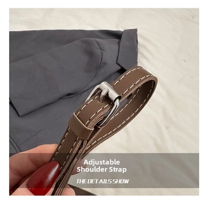 Macro detail of brown leather shoulder strap with silver buckle and white stitching