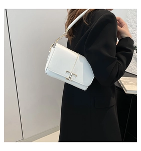 Détail du sac à main en cuir verni blanc avec boucle en métal T doré et bandoulière chaîne