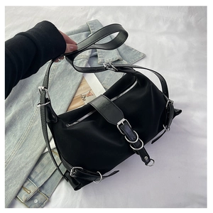 Detail of black nylon shoulder bag with adjustable leather buckles and silver hardware