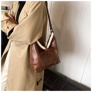 Detail of faux fur trim and toggle closure on brown leather bucket bag for autumn