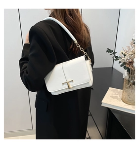 Détail du sac bandoulière en cuir blanc avec fermoir en T doré et chaîne sur modèle