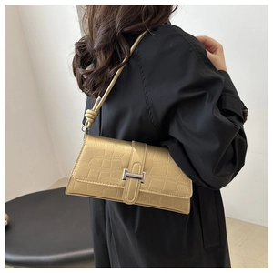 Close-up of beige faux-crocodile skin texture and silver H-shaped metal buckle on bag