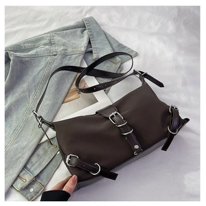 Detail view of brown crossbody bag with silver buckles and mixed fabric texture