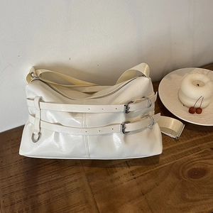 Creamy white patent leather shoulder bag with buckle straps and pleated texture